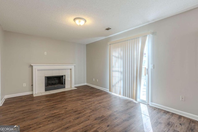 unfurnished living room with a tile fireplace, a textured ceiling, and dark hardwood / wood-style floors