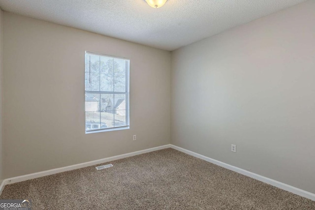 empty room featuring a textured ceiling and carpet