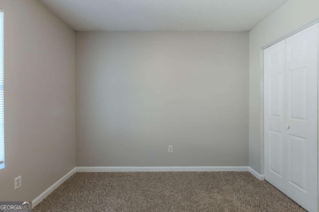 unfurnished bedroom featuring a textured ceiling, a closet, and carpet flooring