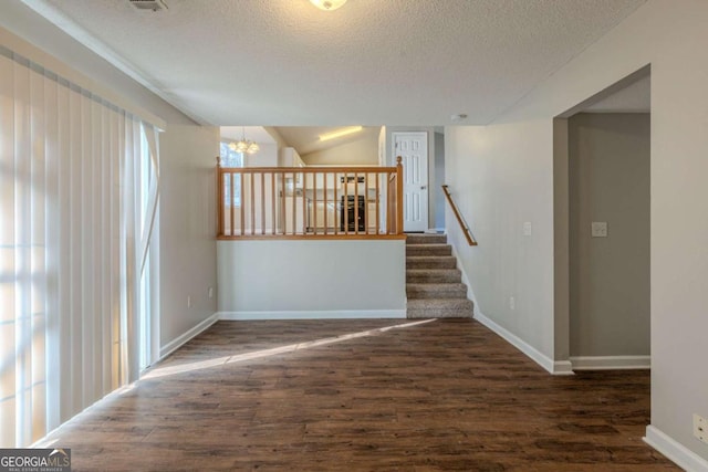 interior space featuring a chandelier, dark wood-type flooring, a textured ceiling, and lofted ceiling