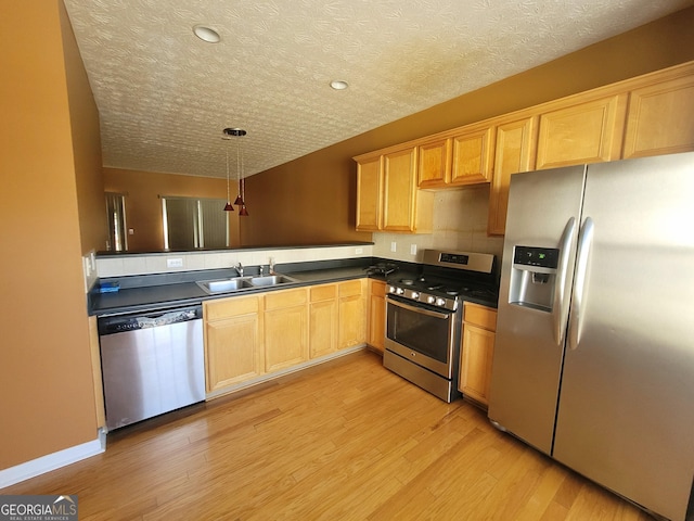 kitchen with sink, hanging light fixtures, light hardwood / wood-style flooring, and appliances with stainless steel finishes