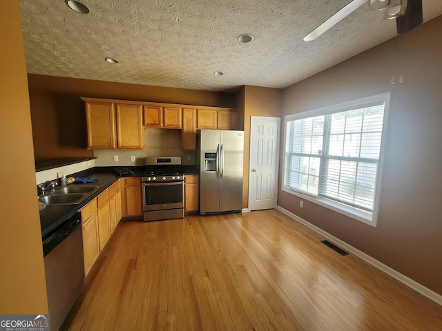 kitchen with ceiling fan, appliances with stainless steel finishes, sink, light wood-type flooring, and a textured ceiling