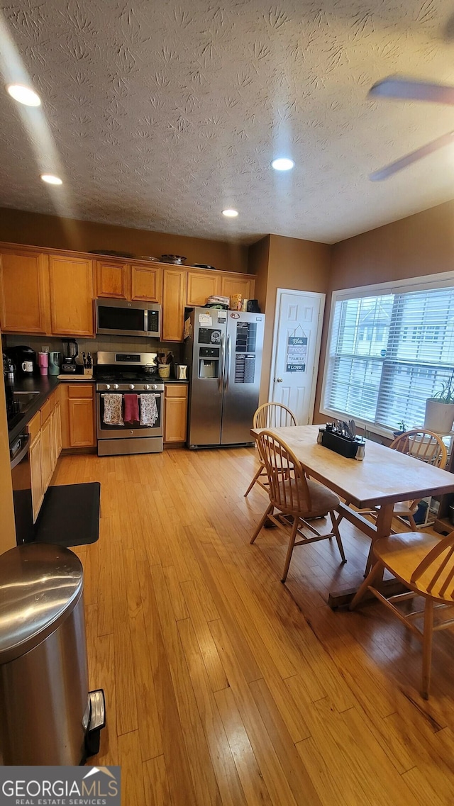 kitchen featuring light hardwood / wood-style floors, a textured ceiling, and appliances with stainless steel finishes