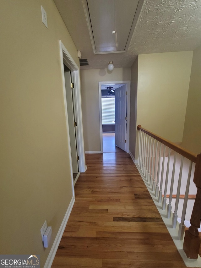 hallway with light hardwood / wood-style floors and a textured ceiling