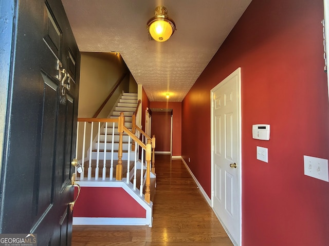 foyer entrance with hardwood / wood-style floors and a textured ceiling