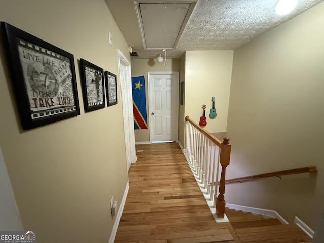 corridor with light hardwood / wood-style floors and a textured ceiling