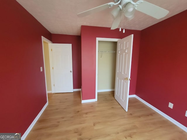 unfurnished bedroom with ceiling fan, a closet, and light wood-type flooring