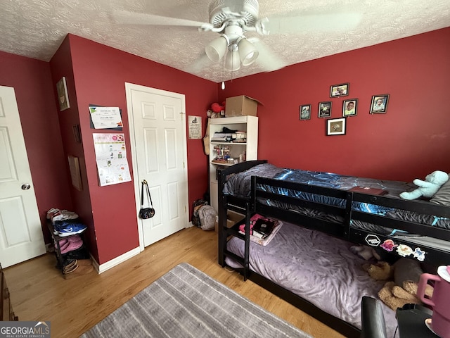 bedroom featuring hardwood / wood-style flooring, a textured ceiling, and ceiling fan