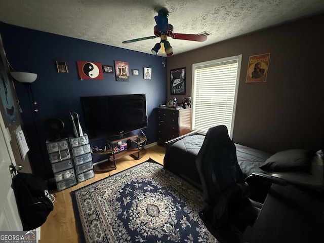 bedroom featuring ceiling fan, a textured ceiling, and wood-type flooring