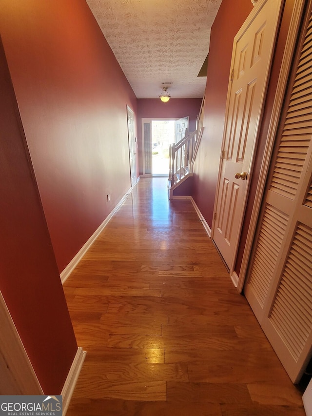 hall with wood-type flooring and a textured ceiling