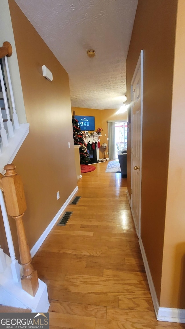 hallway featuring light wood-type flooring and a textured ceiling