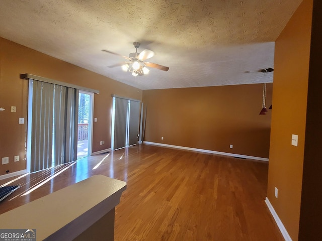 interior space with ceiling fan, a textured ceiling, and wood-type flooring