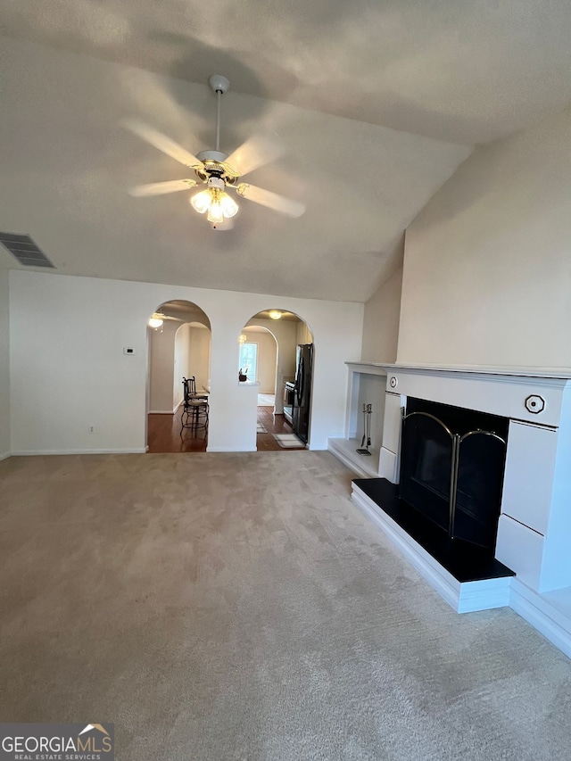 unfurnished living room featuring ceiling fan, lofted ceiling, and carpet