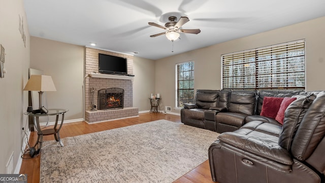 living room featuring ceiling fan, a fireplace, and light hardwood / wood-style flooring