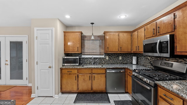 kitchen featuring sink, decorative backsplash, hanging light fixtures, stainless steel appliances, and french doors