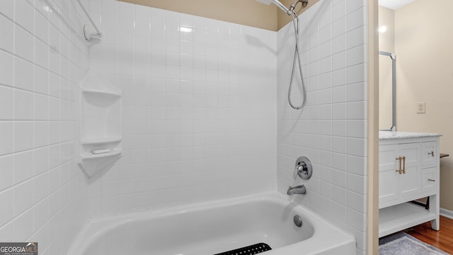 bathroom featuring hardwood / wood-style flooring, tiled shower / bath, and vanity