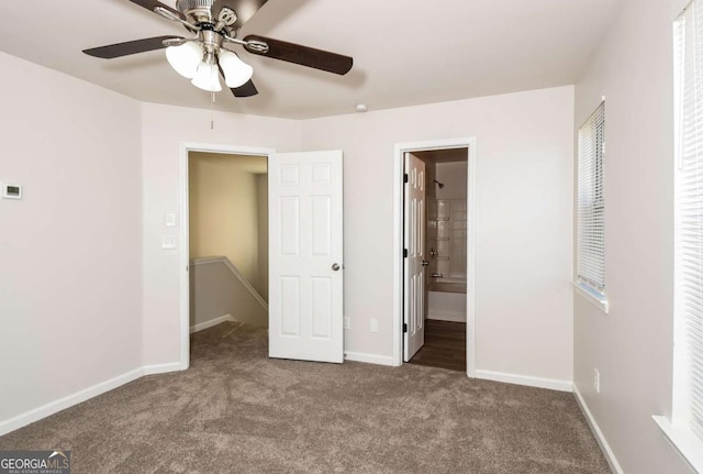 unfurnished bedroom with ceiling fan, a walk in closet, ensuite bath, and carpet flooring