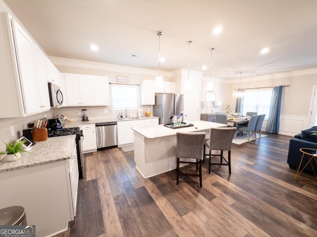 kitchen with sink, a center island, hanging light fixtures, stainless steel appliances, and white cabinets