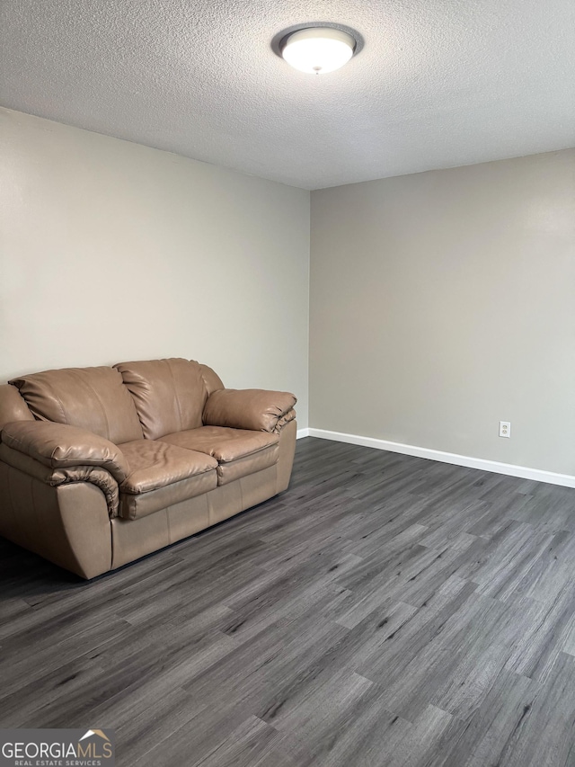 unfurnished living room with dark hardwood / wood-style flooring and a textured ceiling