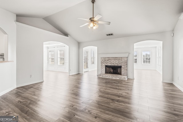 unfurnished living room featuring dark hardwood / wood-style flooring, a brick fireplace, lofted ceiling, and ceiling fan