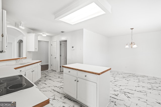 kitchen with sink, decorative light fixtures, a center island, a chandelier, and white cabinets