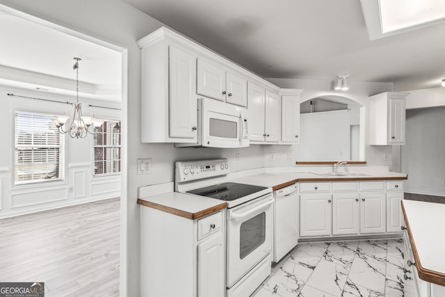 kitchen with sink, white appliances, hanging light fixtures, and white cabinets