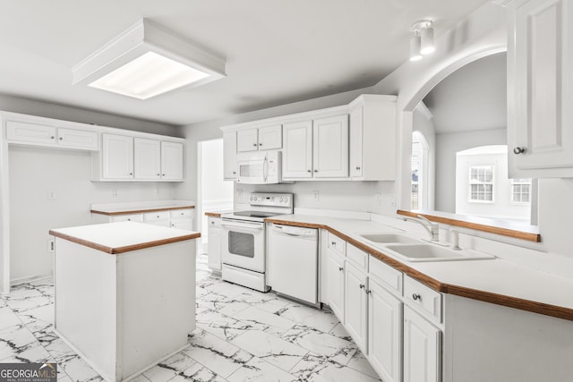 kitchen with white appliances, a center island, sink, and white cabinets