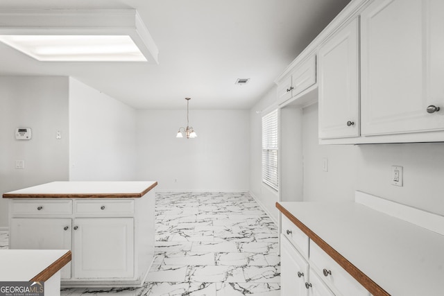 kitchen featuring a notable chandelier, pendant lighting, and white cabinets