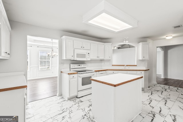 kitchen featuring white cabinetry, a center island, and white appliances