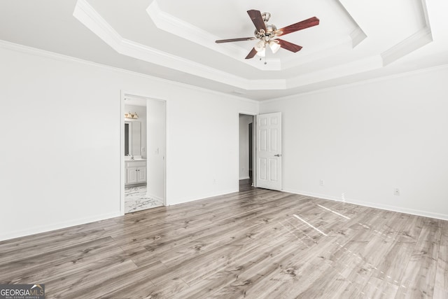 empty room with ceiling fan, ornamental molding, a raised ceiling, and light hardwood / wood-style flooring