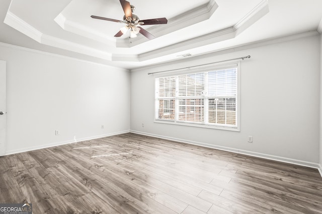 spare room featuring hardwood / wood-style flooring, ceiling fan, ornamental molding, and a raised ceiling