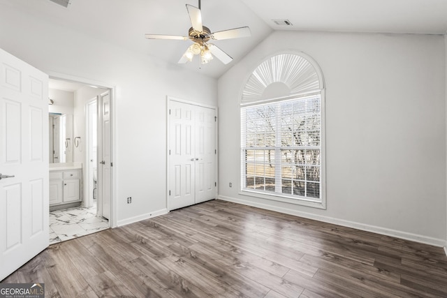 unfurnished bedroom with vaulted ceiling, connected bathroom, ceiling fan, and light hardwood / wood-style flooring