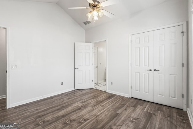 unfurnished bedroom with lofted ceiling, a closet, dark hardwood / wood-style floors, and ceiling fan