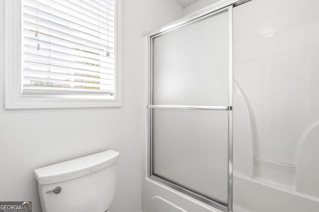 bathroom with toilet and combined bath / shower with glass door