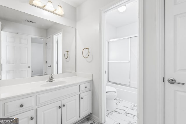 full bathroom featuring vanity, bath / shower combo with glass door, and toilet