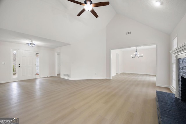 unfurnished living room with a fireplace, ceiling fan with notable chandelier, light hardwood / wood-style flooring, and high vaulted ceiling