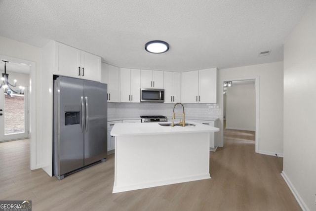 kitchen featuring sink, white cabinets, backsplash, an island with sink, and stainless steel appliances