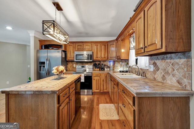 kitchen with a kitchen island, pendant lighting, sink, stainless steel appliances, and crown molding