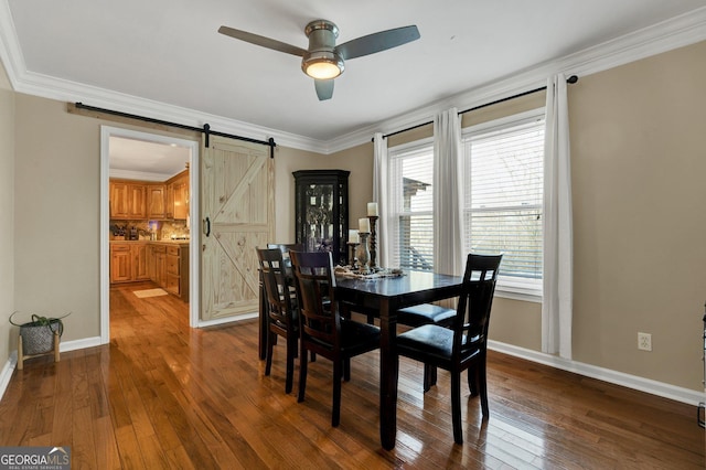 dining space featuring wood-type flooring, a barn door, ornamental molding, and ceiling fan