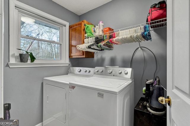 laundry room featuring washing machine and dryer, cabinets, and a textured ceiling