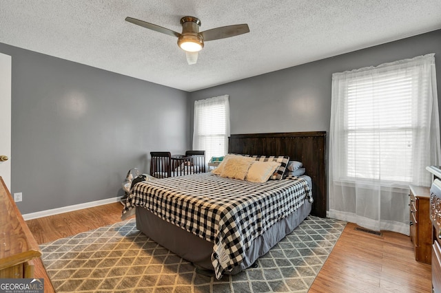 bedroom with hardwood / wood-style floors, a textured ceiling, and ceiling fan