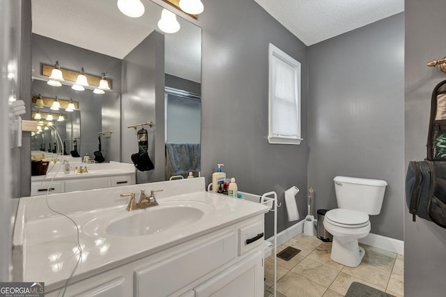 bathroom with tile patterned flooring, vanity, toilet, and a textured ceiling