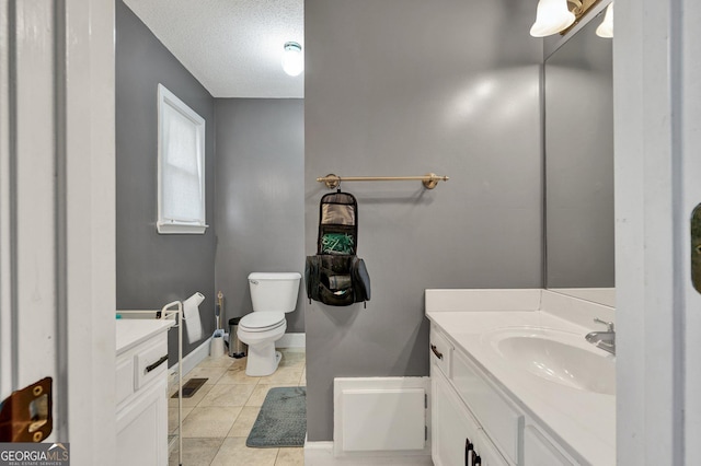 bathroom with tile patterned floors, vanity, toilet, and a textured ceiling