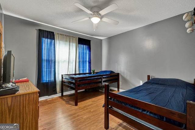 bedroom featuring ceiling fan, hardwood / wood-style floors, and a textured ceiling