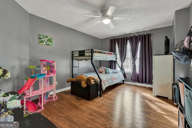 bedroom with ceiling fan, hardwood / wood-style floors, and a textured ceiling