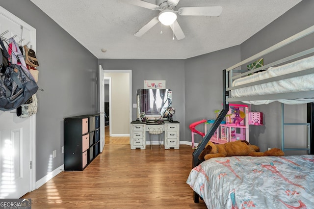 bedroom with wood-type flooring, ceiling fan, and a textured ceiling