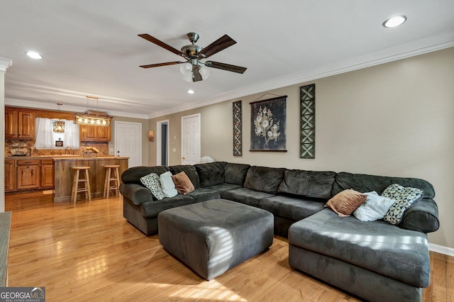 living room featuring crown molding, ceiling fan, and light wood-type flooring