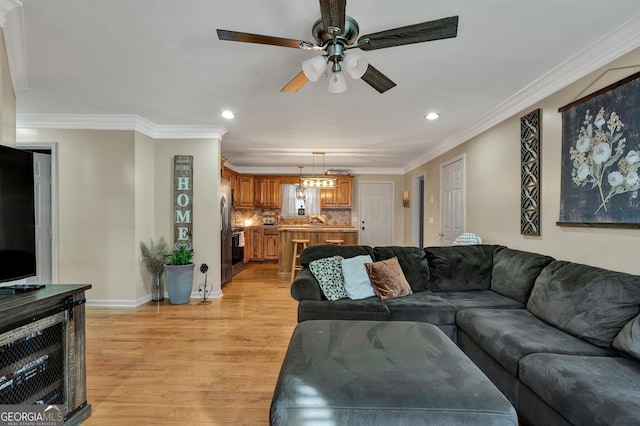 living room with crown molding, ceiling fan, and light wood-type flooring