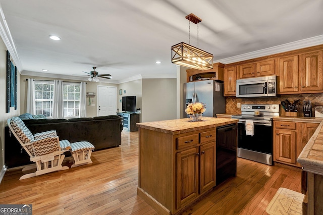 kitchen featuring hanging light fixtures, crown molding, appliances with stainless steel finishes, and a center island