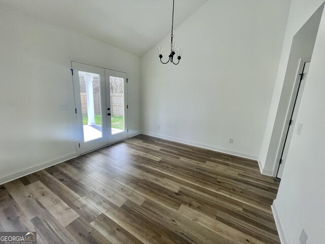 unfurnished living room featuring ceiling fan with notable chandelier, dark wood-type flooring, high vaulted ceiling, and french doors